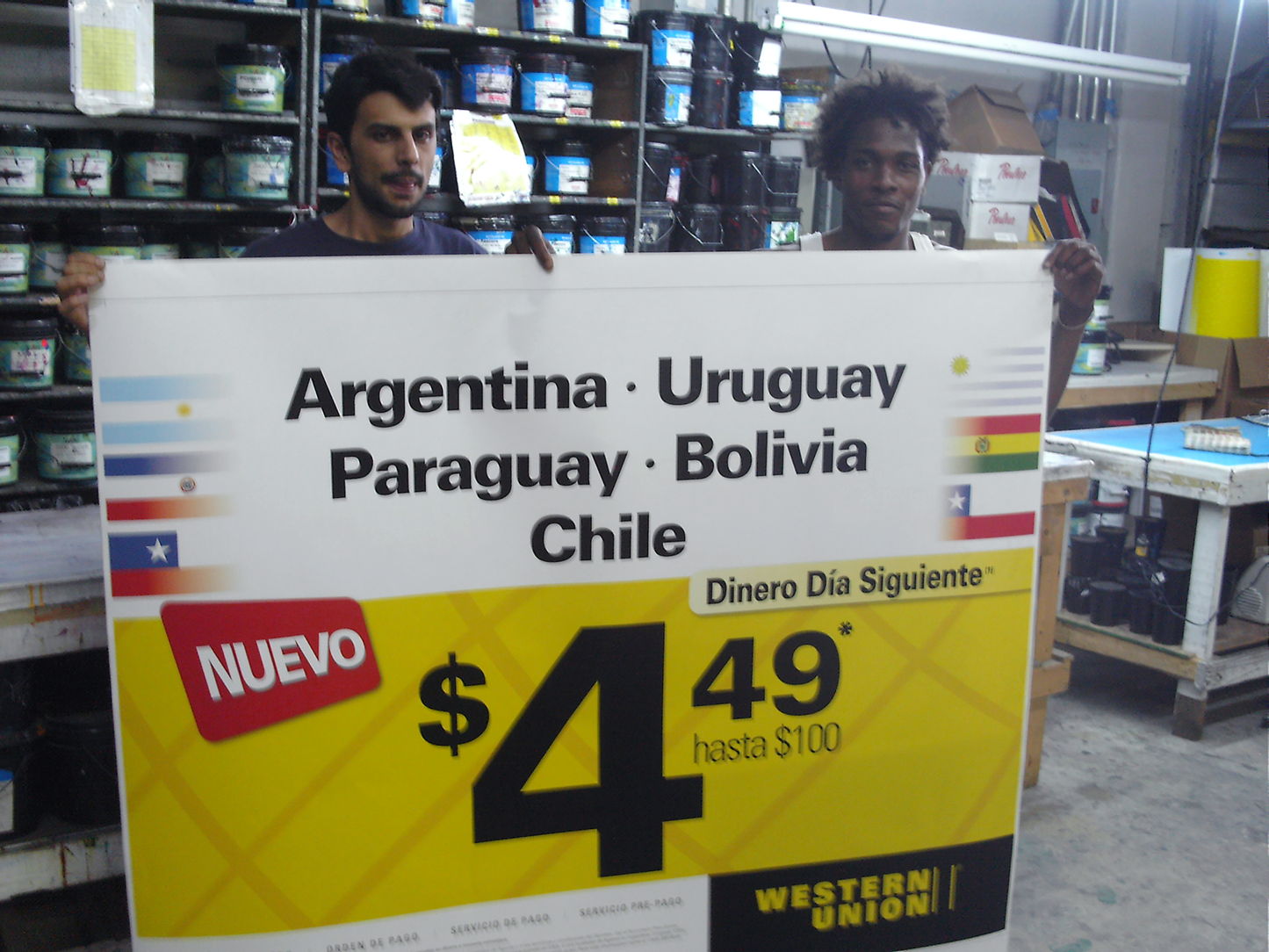 KAWAN AND TONY holding a Western Union sign in a store setting with shelves and products in the background.