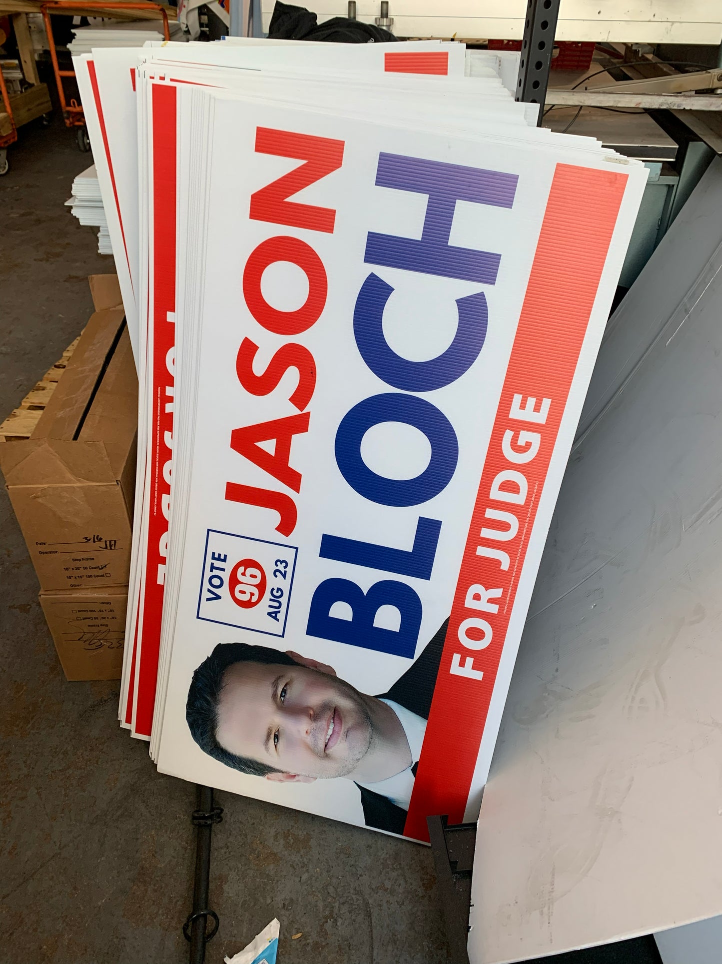 Stack of political campaign signs for Jason Bloch with a photo 