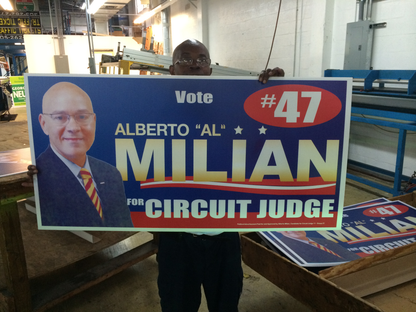 Person holding a political campaign sign for Alberto 'Al' Milian for Circuit Judge.