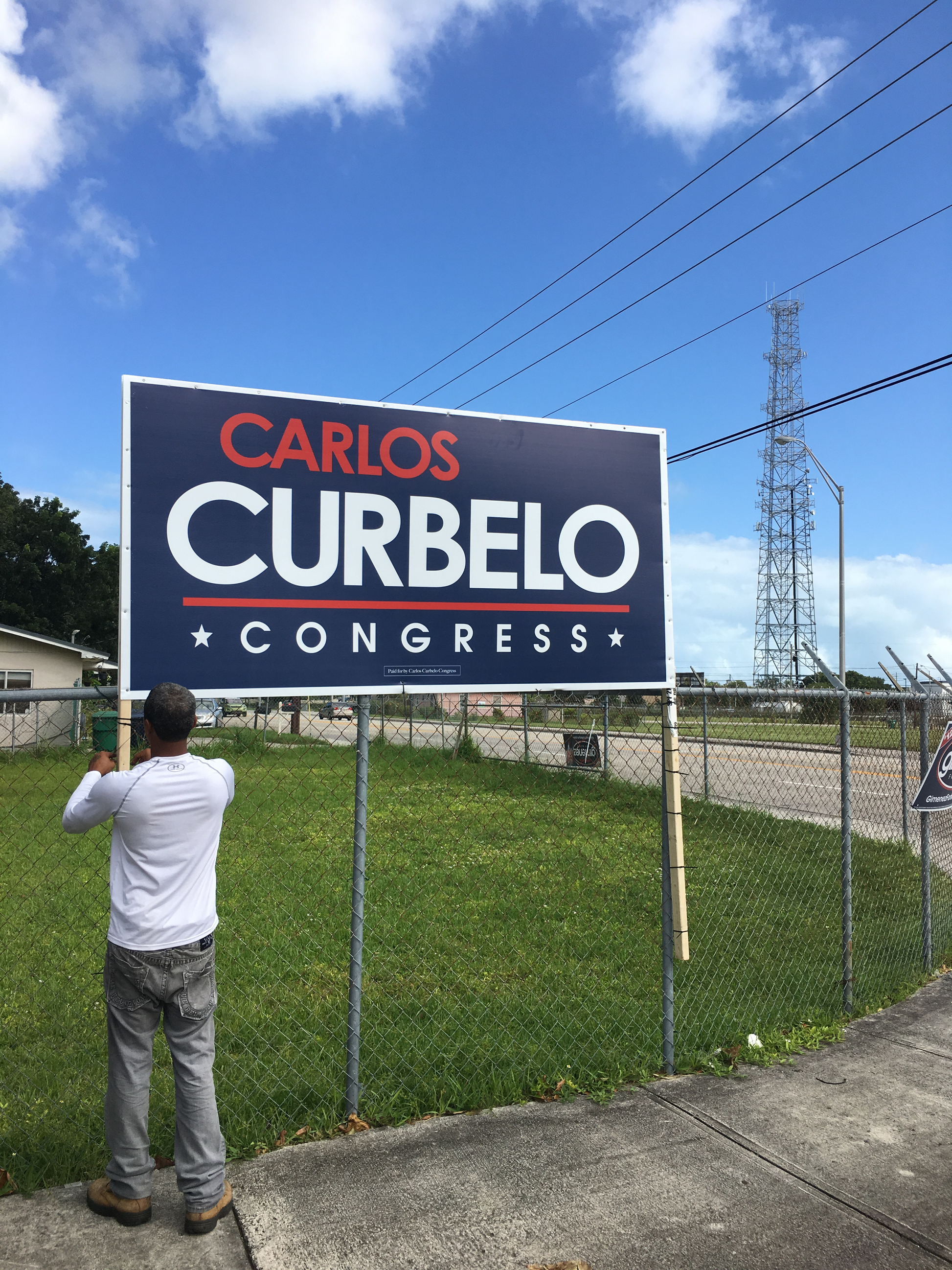 Person taking a photo of a political campaign sign for Carlos Curbelo in Congress.
